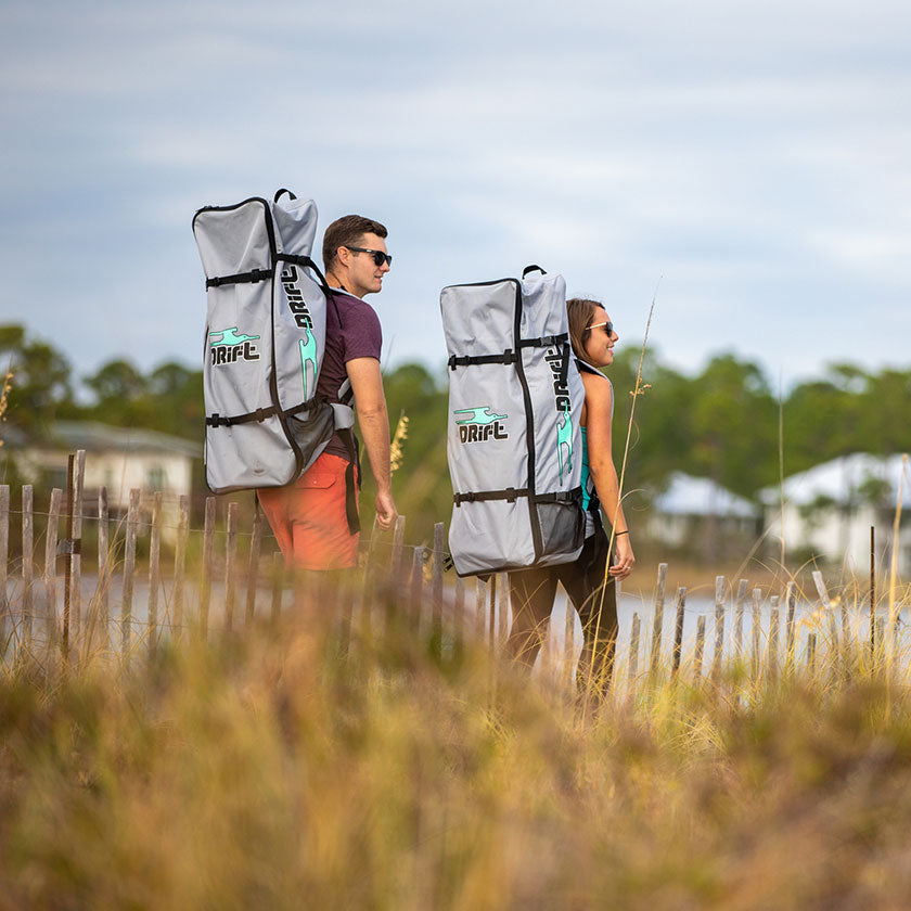 people carrying paddle boards in their bags